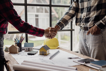 Close-up photo of architect and construction engineer holding hands while working for teamwork and...