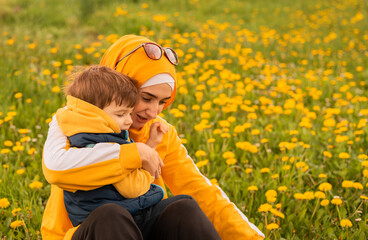 Happy Muslim family having fun mother and child boy playing together with dandelion in the flowering spring field. © Malik Nalik