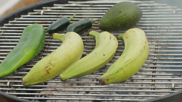 Grilled Banana on fire, latin american vegan grill with avocado and pepper, thai or Ecuadorian Street food. African traditional food on grill. 
