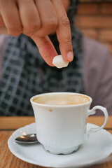  woman hand pouring white sugar cube in a coffee cup ,