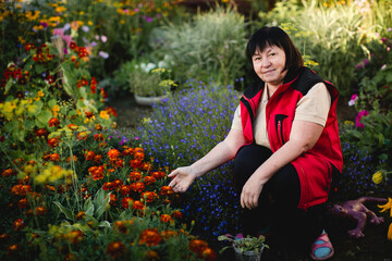 A woman poses in her flower garden. - 767543342