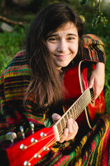 A girl playing guitar sitting in a summer garden. - 767543360