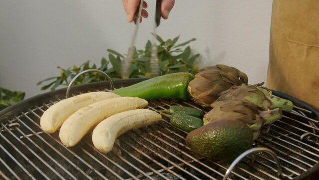 Grilled Banana on fire, latin american vegan grill with avocado and pepper, thai or Ecuadorian Street food. African traditional food on grill. 