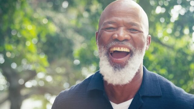 Portrait smiling and laughing senior man standing outdoors in countryside or garden - shot in slow motion