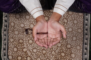 overhead shot of muslim person doing prayer with beads on hand