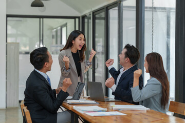Smiling Asian businessman raising his hands Clapping happily at the table in the office Group of successful Asian business teams discuss cooperation Presentation and analysis of successful reports.