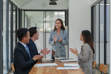 Smiling Asian businessman raising his hands Clapping happily at the table in the office Group of successful Asian business teams discuss cooperation Presentation and analysis of successful reports.