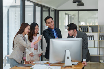 Fototapeta premium Smiling Asian businessman raising his hands Clapping happily at the table in the office Group of successful Asian business teams discuss cooperation Presentation and analysis of successful reports.