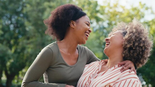 Family portrait shot with senior mother talking and laughing with adult daughter outdoors in countryside - shot in slow motion