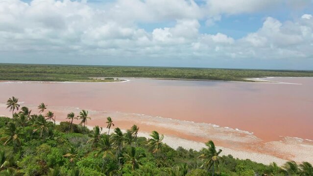 Parallax drone shot of a pink lake and the ocean during daytime.