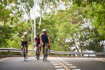 group of three young asian adult cyclists riding bike on rural road