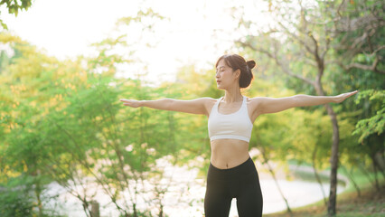 Female jogger. Fit young Asian woman with sportswear stretching muscle in park before running and...