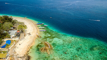Aerial view of tourist boats over the coral reef flat on a small tropical island