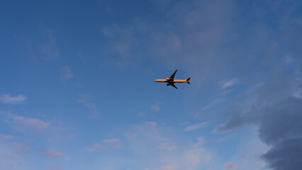 A plane flying in blue sky catching sunlight.