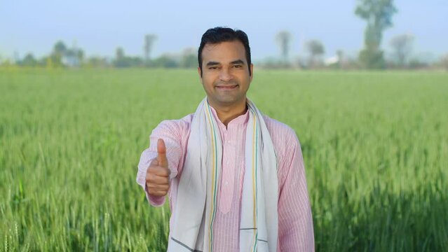 Portrait shot of a young Indian village man doing thumbs up - rural area  village lifestyle  rural development  farming. New-age farmer showing great success through gestures - happy farmer  desi I...