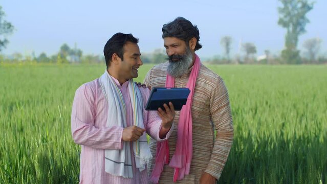 Young educated villager teaching grey-haired farmer - modern agriculture  tab  technology in village  advanced farming. Aged village man learning the new benefits of government schemes through tab ...