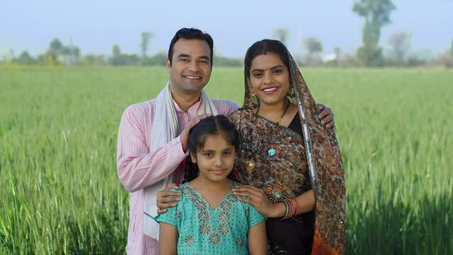 Young age farmer happily posing with his family - village couple  desi family  rural lifestyle  nuclear family  girl child. A village couple spending quality family time with their daughter - small...