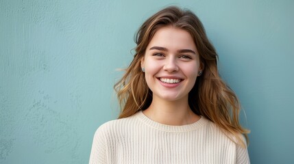 Radiant young woman with a charming smile standing against a textured teal background - obrazy, fototapety, plakaty