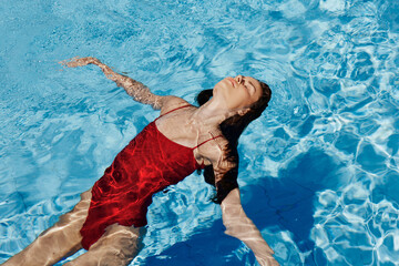 Happy woman swimming in pool in red swimsuit with loose long hair, skin protection with sunscreen,...