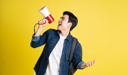 Portrait of Asian male student posing on yellow background