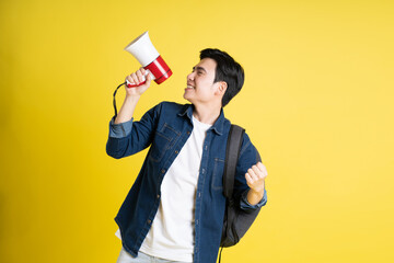 Portrait of Asian male student posing on yellow background