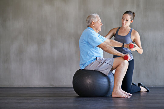 Physical therapy, dumbbells and elderly man on ball for fitness, rehabilitation or exercise at gym on mockup. Senior person, weightlifting and personal trainer help for body health or physiotherapy
