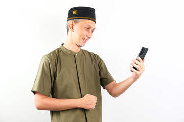 Asian moslem man showing happy expression and smiling with holding his mobile phone. 
