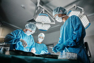 Surgeon group, procedure and operating room at hospital in scrubs, ppe and tools for healthcare...