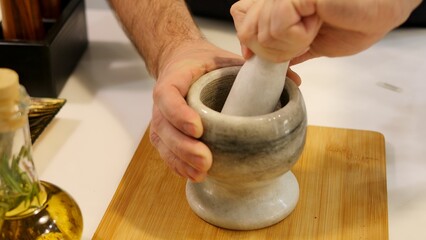 A man grinds spices in a mortar and pestle. The mortar and pestle are essential tools for crushing...