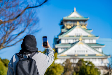 Travel, Muslim travel, Asian Muslim female tourist walking and visitor learning about history at Osaka Castle, Osaka Castle is one of the most famous landmarks in Japan and Osaka, holiday lifestyle.