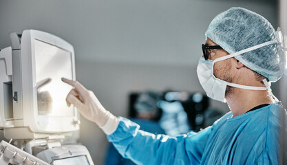 Doctor, scrubs and monitor with machine in theatre for surgery, cardiology analysis and...