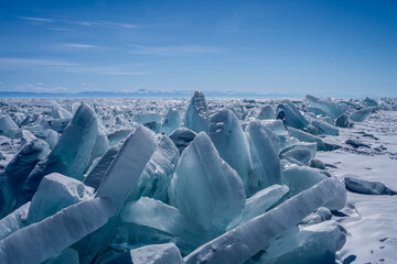 Ice blocks on the beach. Winter landscape with ice hummocks sparkling in the sun on the lake, the sea. High ice piles and blue ice hummocks. Selective focus.