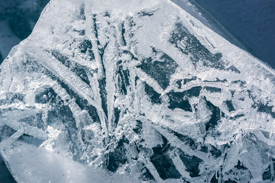 Cracks surface of the frozen lake of Baikal lake in winter season. ice texture cracks baikal, abstract background winter ice transparent blue. Selective focus.