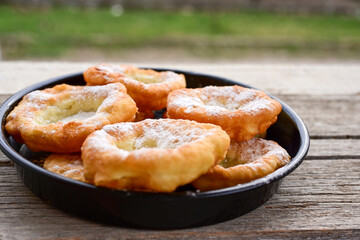 Traditional Bulgarian home made deep fried  patties  covered with sugar  оn rustic backgroud.Mekitsa or Mekica,  on wooden  rustic  background. Made of kneaded dough that is deep fried 