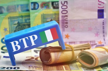 Table with european banknotes as background with the text “BTP” translating as Italian...