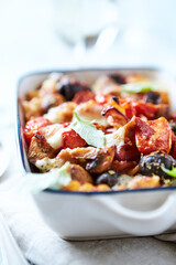 Baked pasta with cherry tomatoes, olives and mozzarella cheese. Bright wooden background. Close up.	