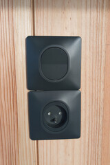 outlet close up grey electrical socket and gray light switch on wooden wall