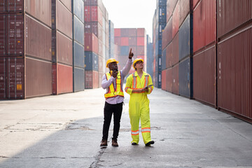 Portrait Asia logistic engineer man worker or foreman use walkie talkie working with African American foreman finger point with container background	 - 767647199