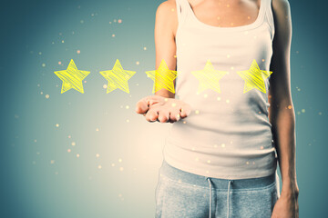 Casual young woman hand holding 5 star rating on concrete wall background. Customer service and...