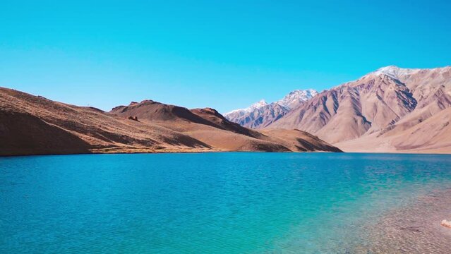 Beautiful Chandra Tal lake with Himalaya mountains in background at Spiti valley, India. Chandrataal lake with blue water during sunny summer day. Summer mountain landscape.