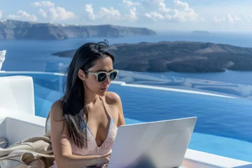 Fototapeten Beautiful asian woman working on laptop computer in luxury hotel on Santorini island, Greece  © PixelGallery
