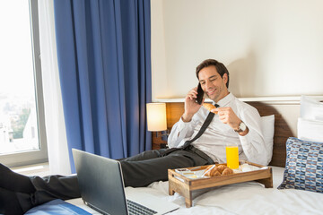 Businessman in suit having breakfast in a hotel bed - 767662746