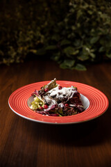 vegan beetroot salad served in red dish in restaurant on dark background