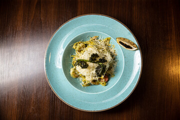 vegetarian pasta pesto served in blue dish in restaurant on dark background