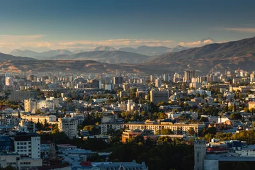 Fotobehang View of Tbilisi from the surrounding hills. In the background you can see the Caucasus Mountains. A warm autumn day in the capital of Georgia. © PawelUchorczak
