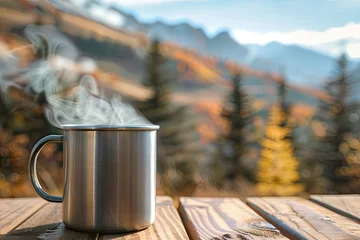Deurstickers Close-up of touristic metal mug with hot tea on a wooden table with the view of autumn forest © Aleksandr Bryliaev