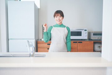 キッチンカウンターに立つエプロン姿の女性