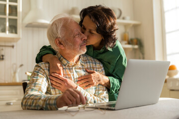 elderly woman kisses and embraces old grey haired husband