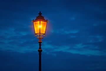 Vintage street lamp glowing against a twilight sky with soft clouds