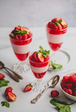 Layered berry, jello and mousse parfait desserts on white background.